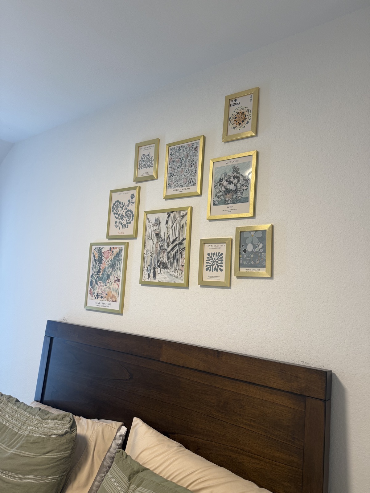 Gallery wall of framed prints hung straight above a bed