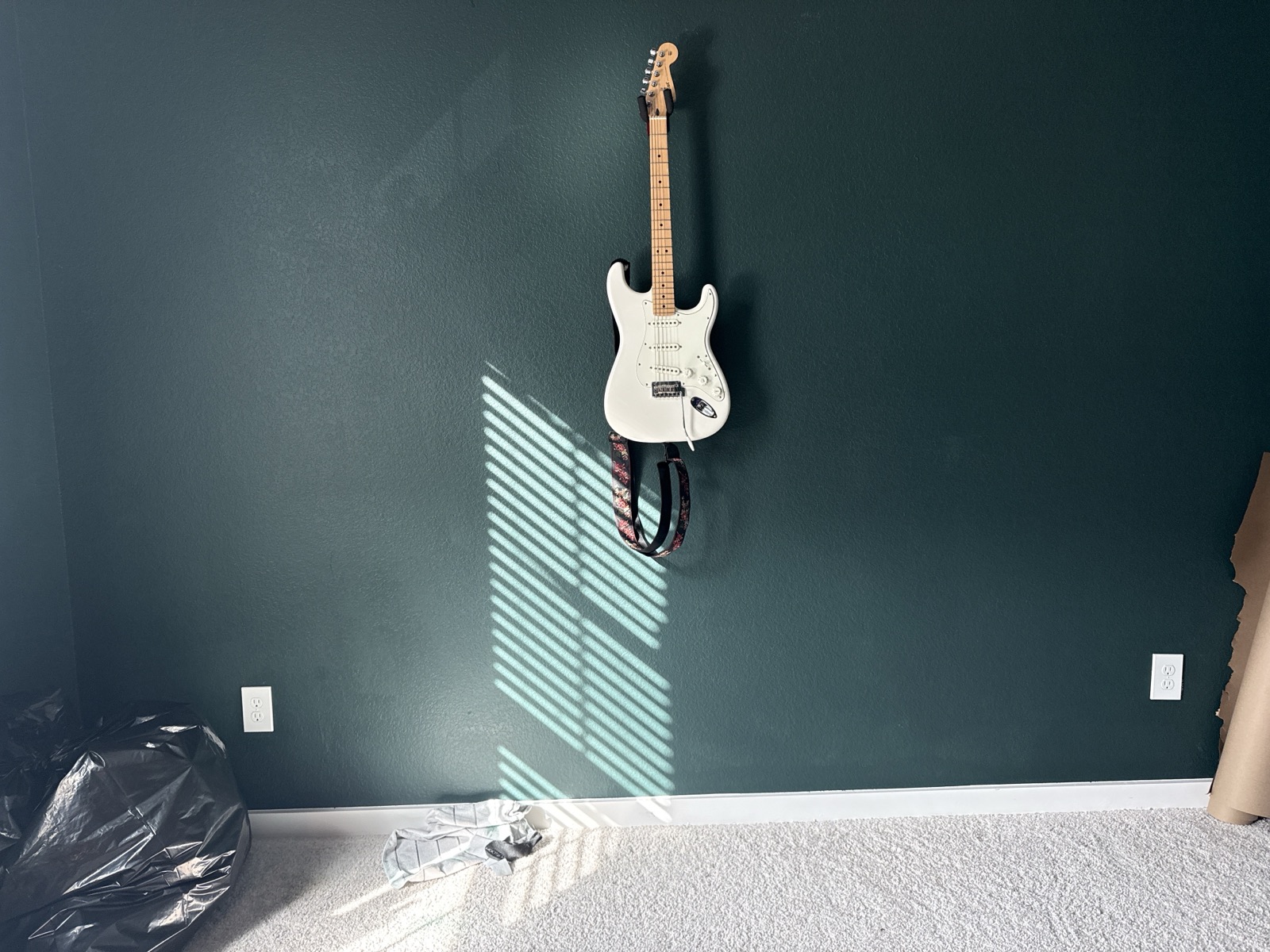 Electric guitar mounted to a deep-green accent wall